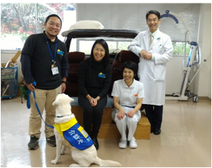 日本介助犬協会のスタッフ２名、当センタースタッフ２名、介助犬が座っている状態で記念写真を撮っている様子